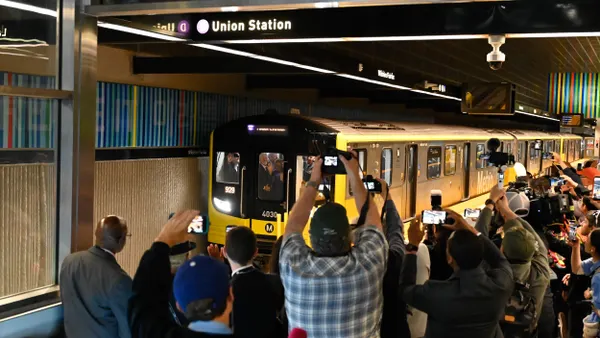 A subway train stops at a station surrounded by photographers and others.