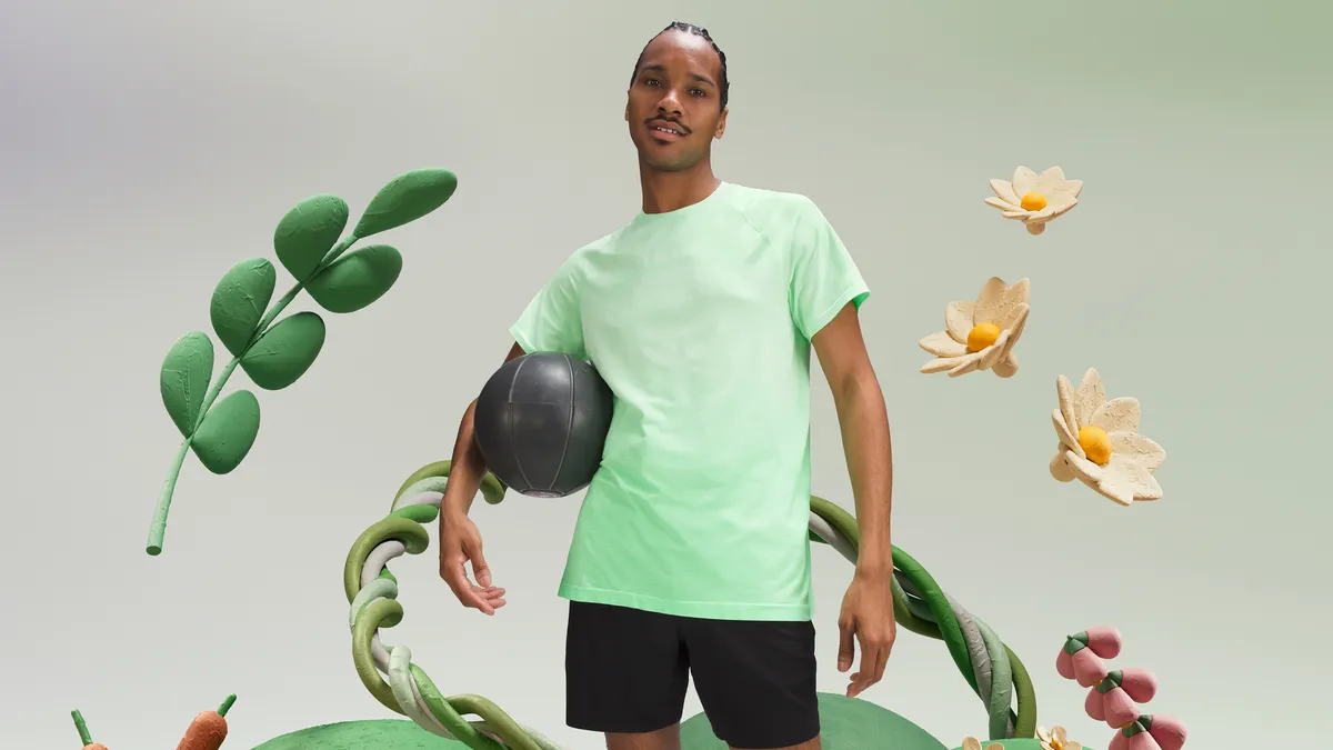 A person in a light green shirt stands in front of plant imagery.