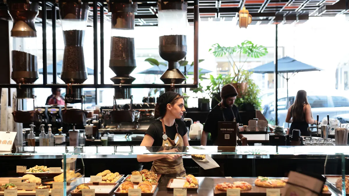 A coffee shop employee prepares an order behind a counter.