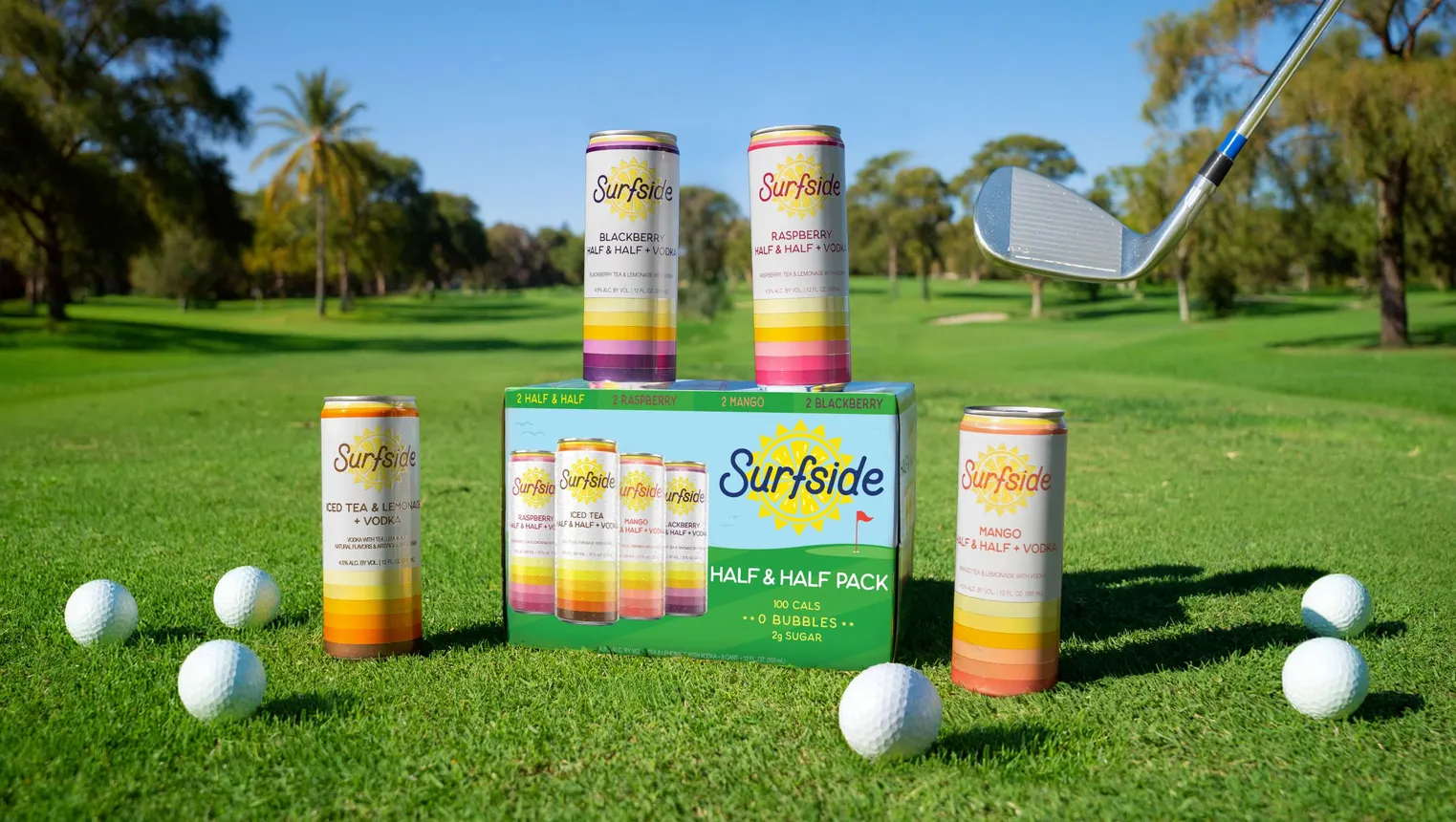 A package of Surfside Half &amp; Half variety pack on a golf course, surrounded by individual cans and golf balls.