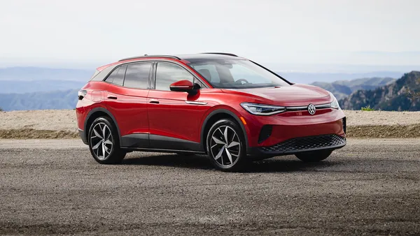 A red 2024 Volkswagen ID.4 SUV on a gravel surface with hills in the background.