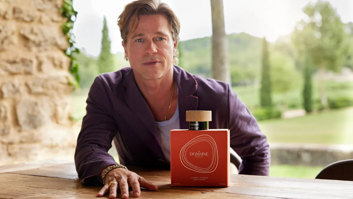 Celebrity Brad Pitt poses with a red bottle of a Le Domaine product.