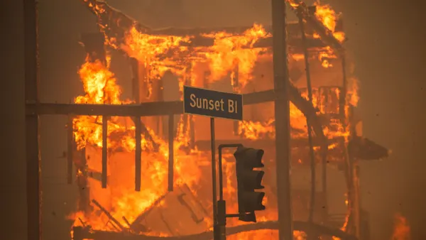 Flames from a fire seen behind a Sunset Blvd. street sign.