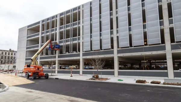 A construction worker on a scissor lift works on a large, under-construction building.