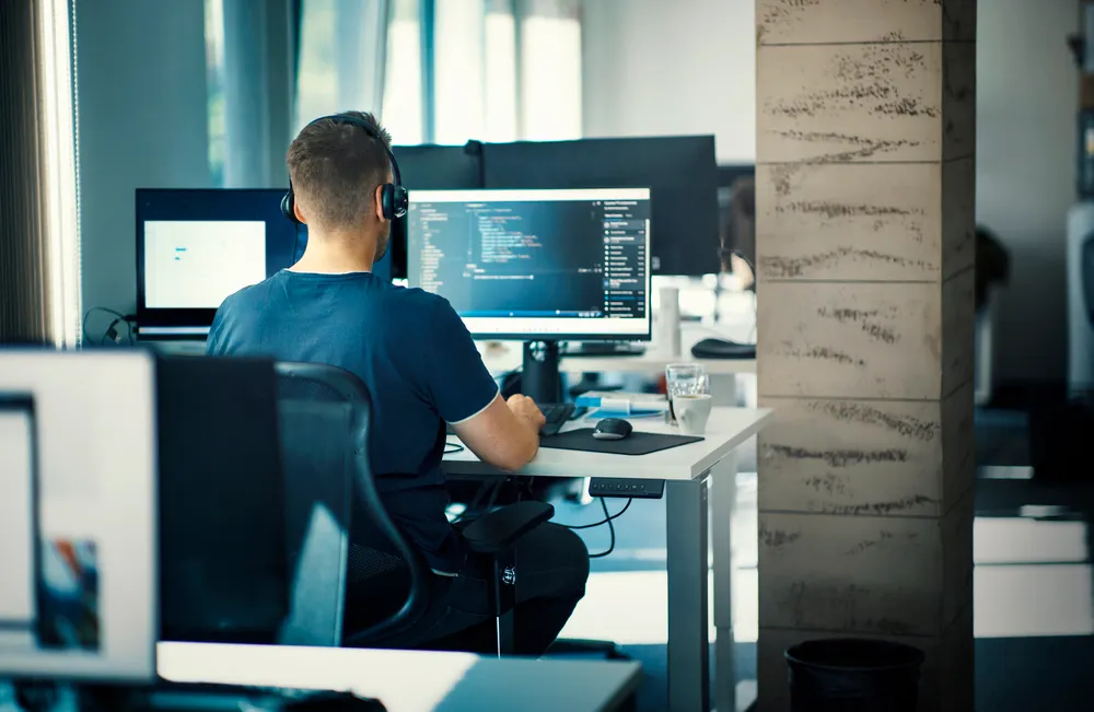 a tech worker sits in front of a terminal in a brightly lit office