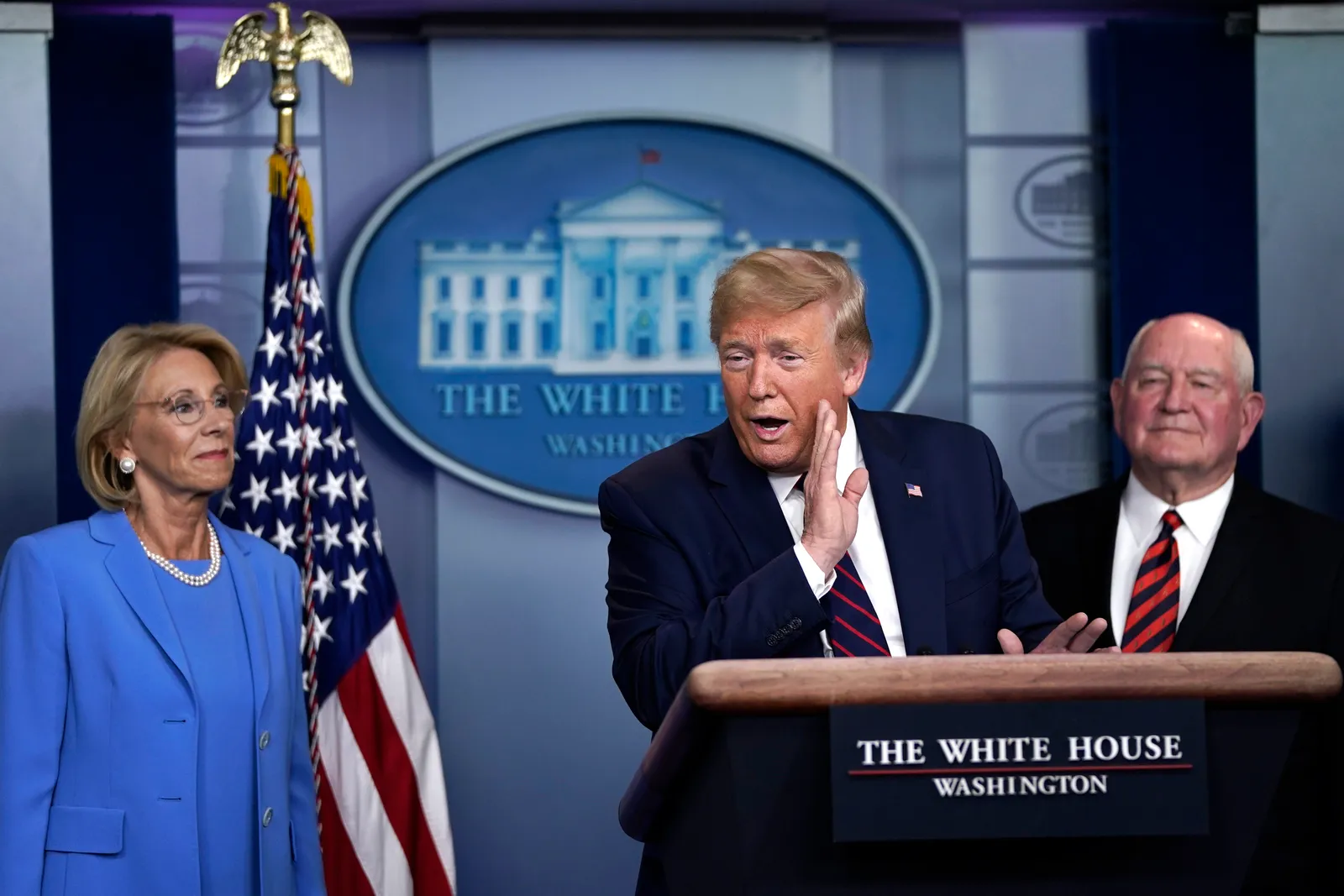 Former President Donald Trump speaks as Secretary of Education Betsy DeVos and Secretary of Agriculture Sonny Perdue look on during a briefing on the coronavirus pandemic.