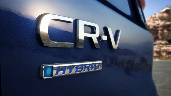 An emblems with the text CR-V and hybrid on the rear of a 2023 dark blue Honda CV-V crossover.