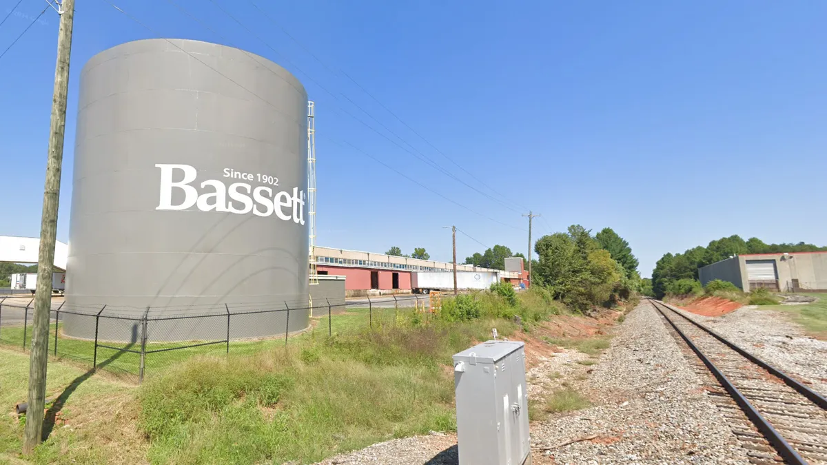 A Bassett Furniture distribution center stands next to train tracks.