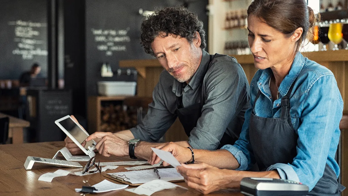 A man and woman looking at receipts inside a cafe