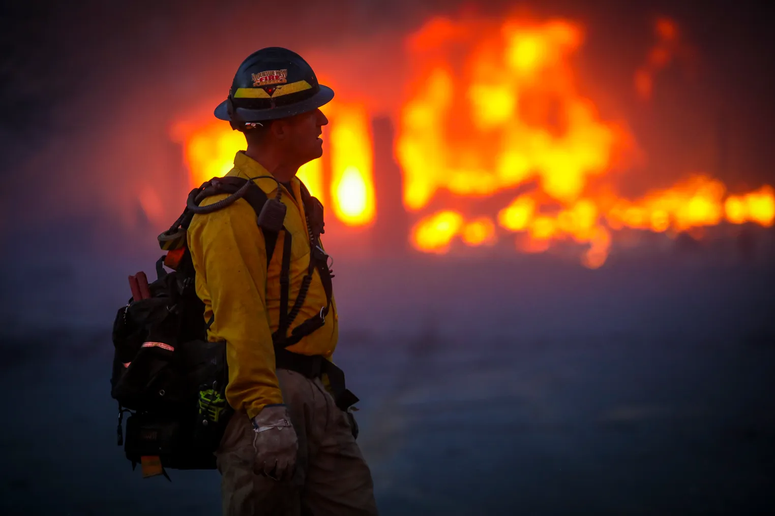 Partial silhouette of a fireman, with a Colorado wildfire burning behind him.