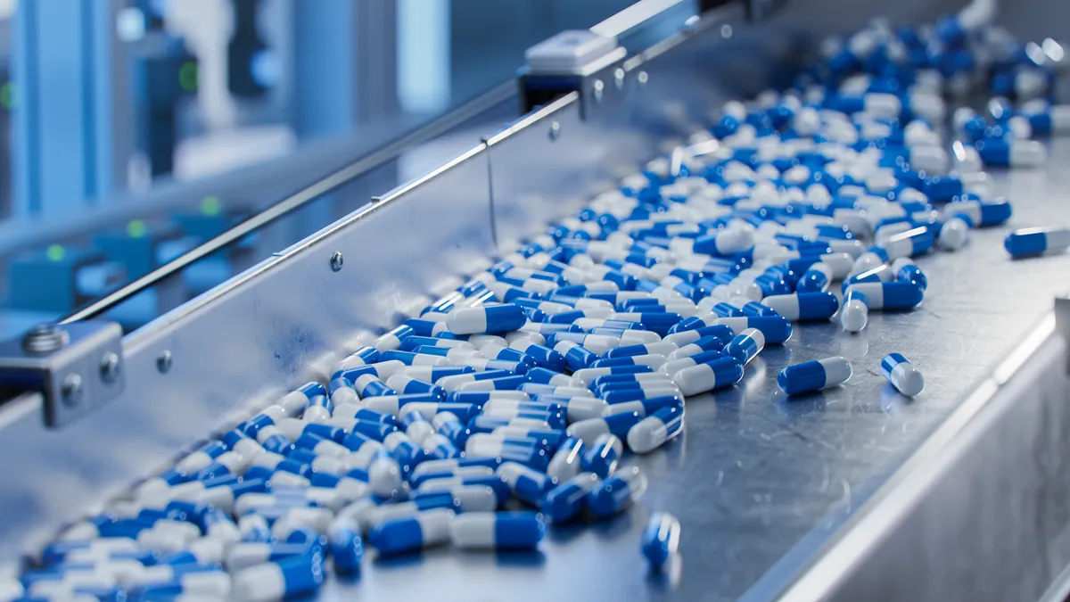 Blue capsules on a conveyor at pharmaceutical factory. Tablet and capsule manufacturing process.