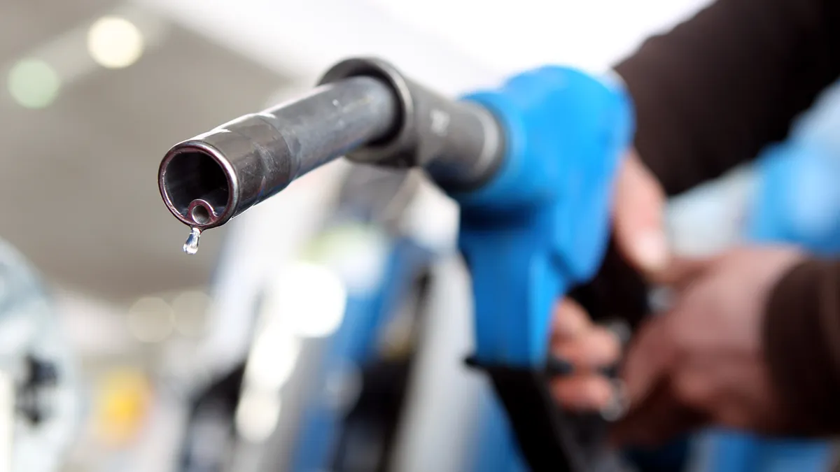 A photo of a person holding the fuelling nozzle of a gas pump.