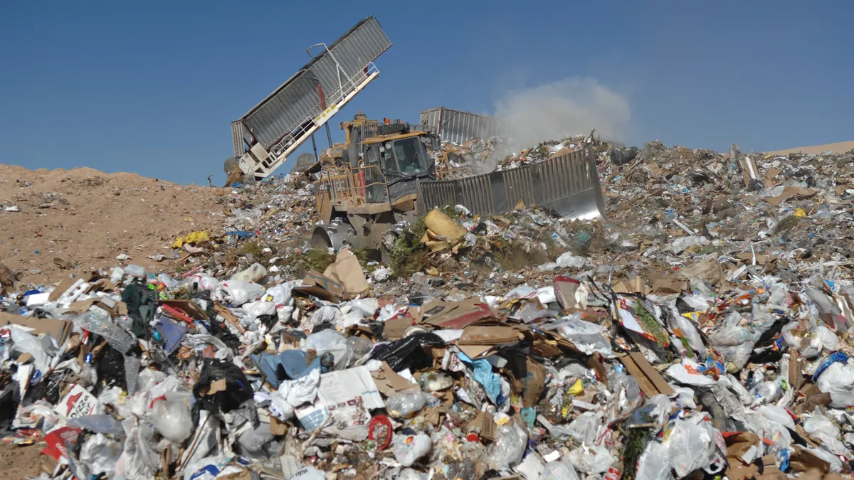 Bulldozer pushing piles of trash in a landfill site