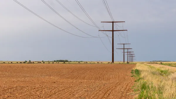 High-voltage power lines crossing a plowed field.