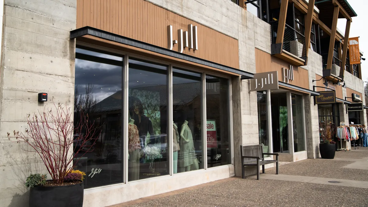 Block letters on wood paneling and a small sign jutting from a light stone building all read "J. Jill," above a store window.