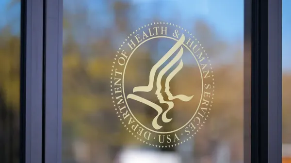 A logo for the U.S. Department of Health and Human Services is displayed on a glass window.