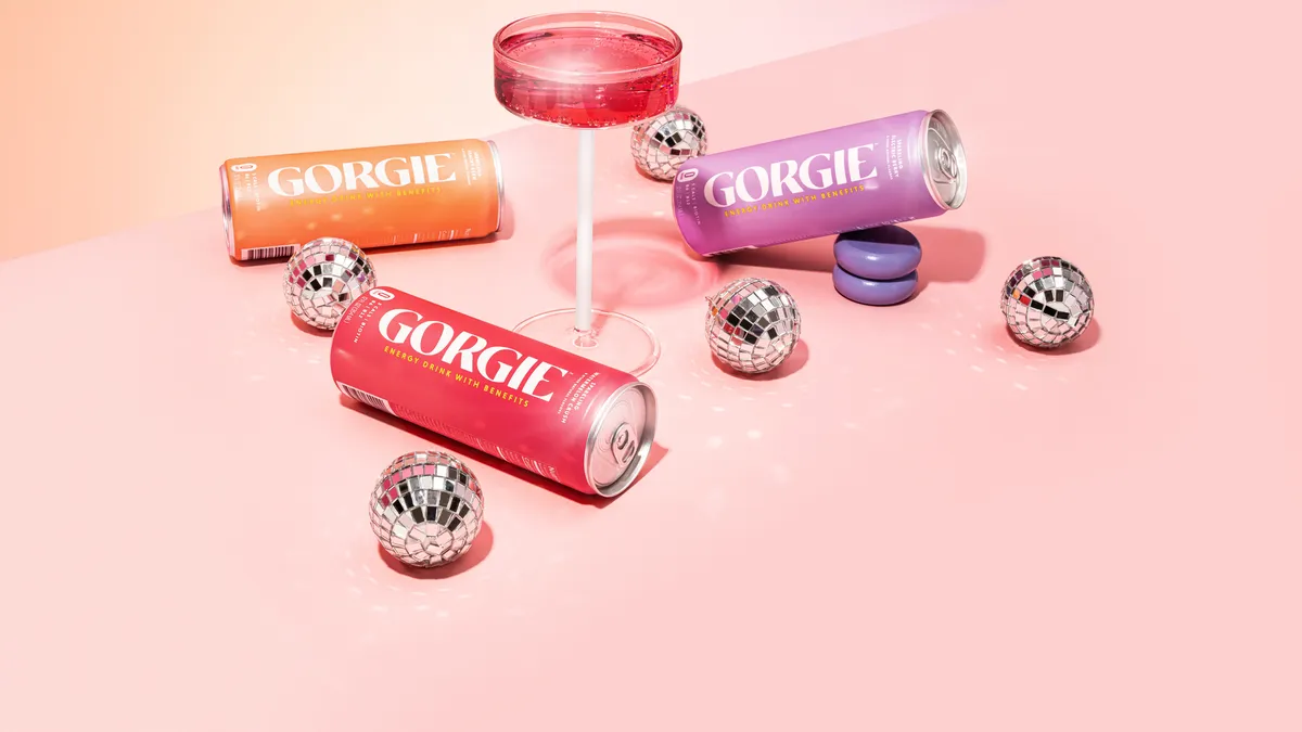 Three pink Gorgie energy drink cans displayed with a pink martini glass