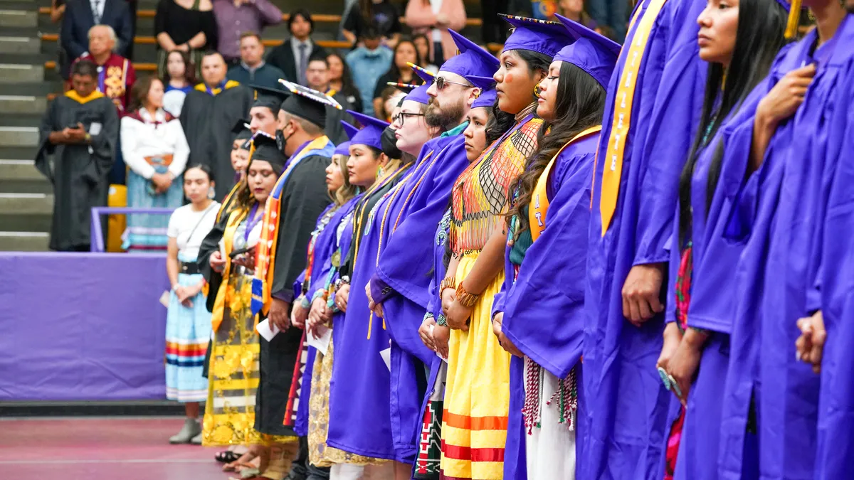 Students stand for a graduation ceremony