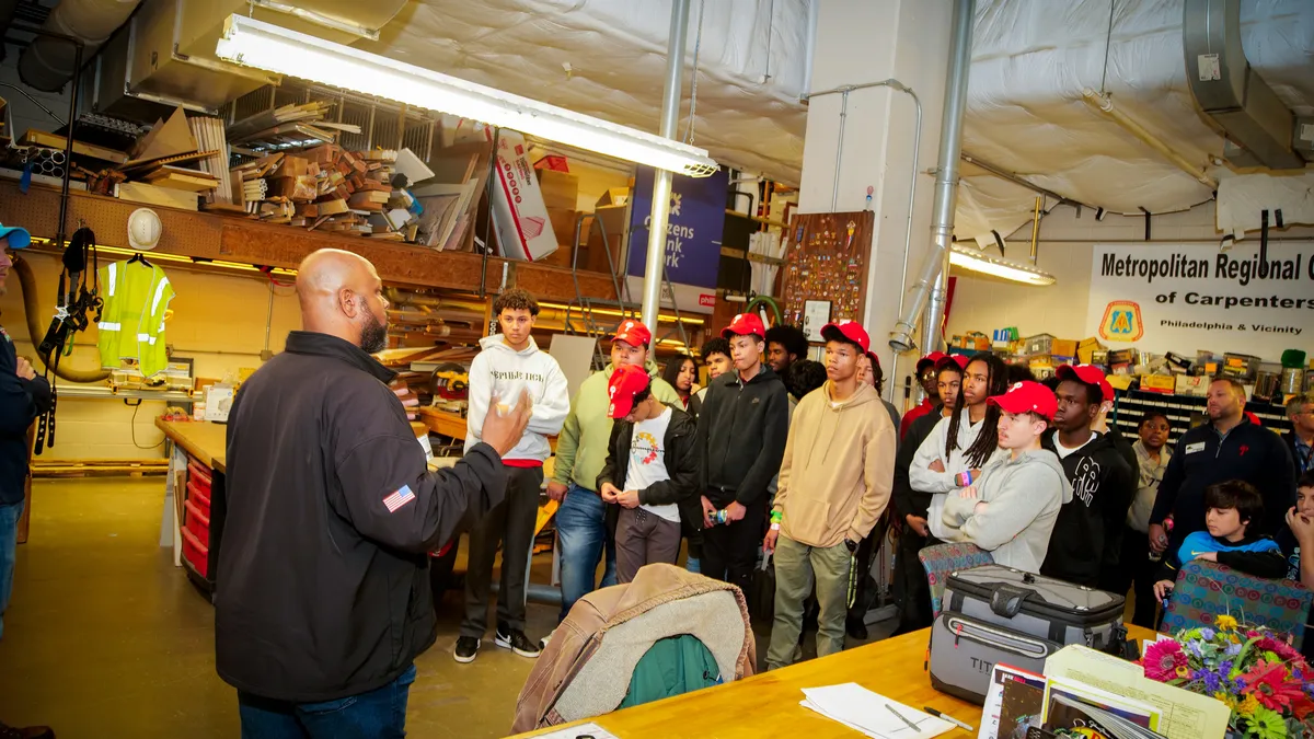 Students listen to a worker cover aspects of HVAC, groundskeeping, carpentry and maintenance at a skilled trades educational program.