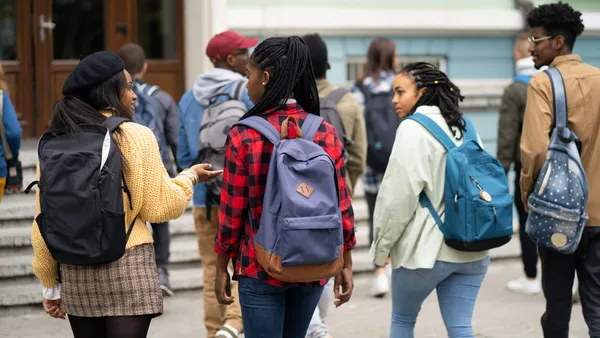 A group of Black students walks on a school campus.