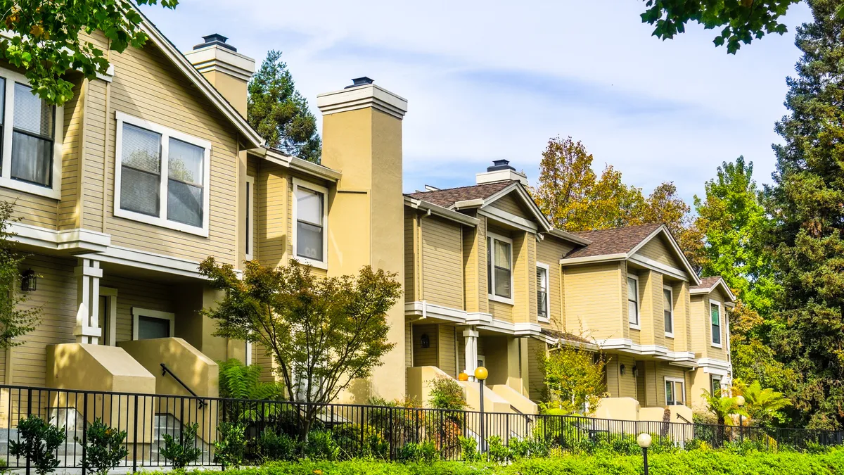 A set of attached homes with yellow siding.