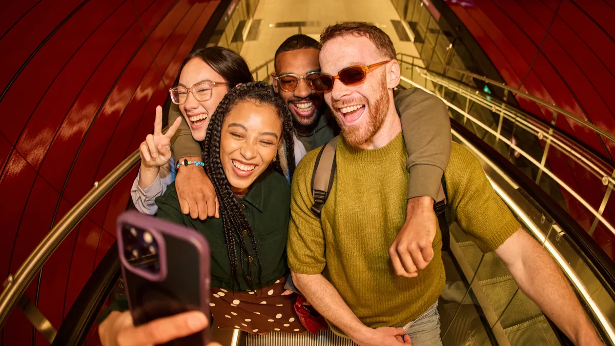 A group of friends take a selfie on the top of an escalator