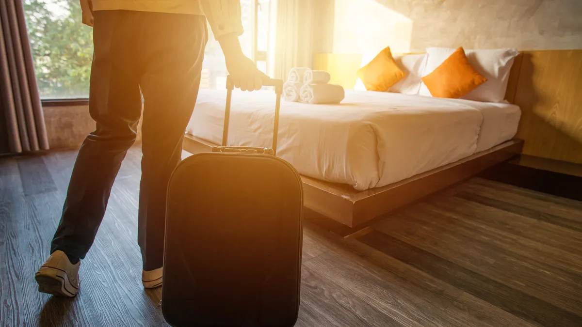 Cropped shot of tourist woman pulling her luggage to her hotel bedroom after check-in.