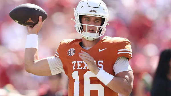 Football player in orange jersey pulling back to throw ball.