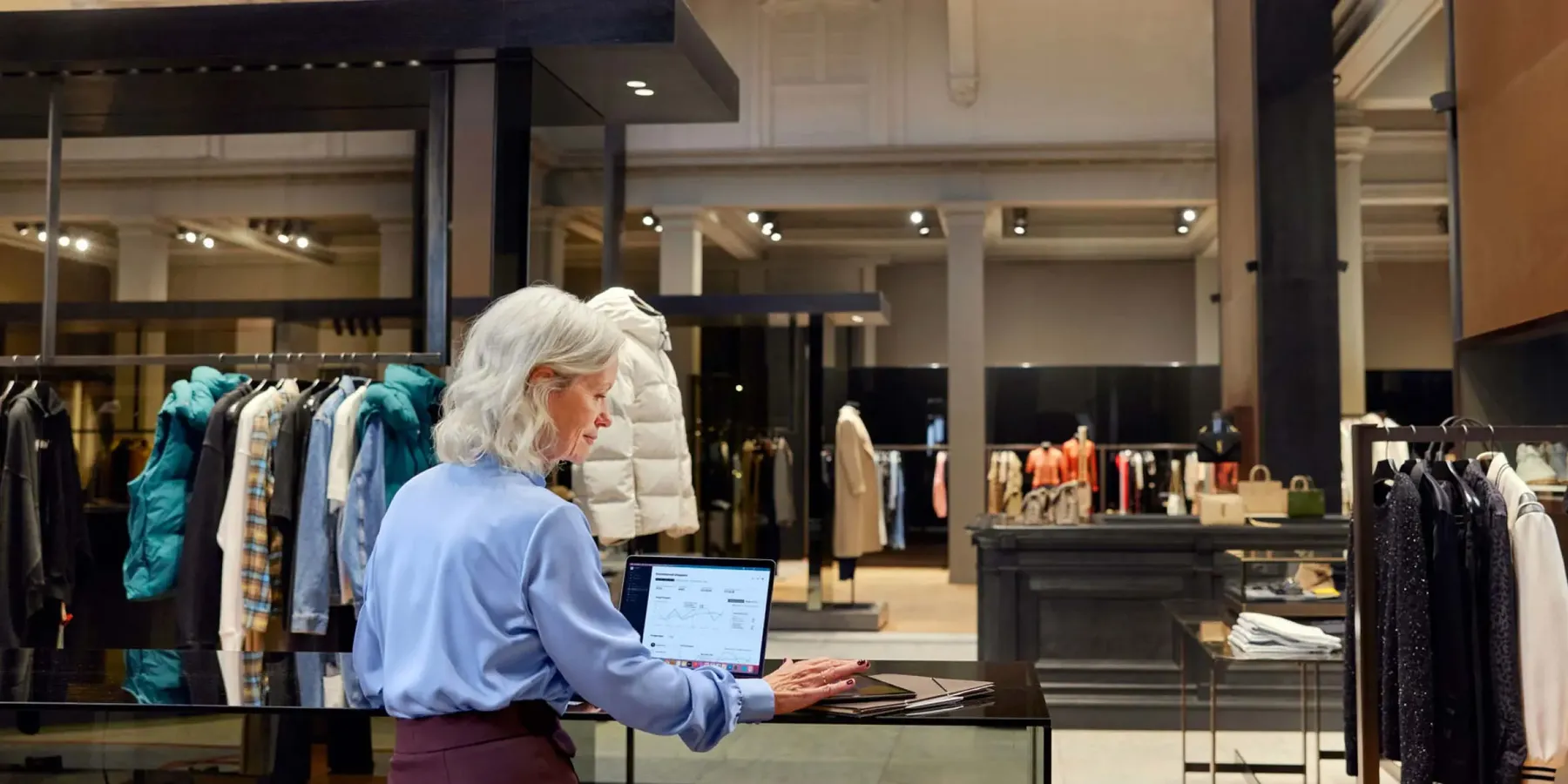 Person working in a clothing retail store touching a tablet.