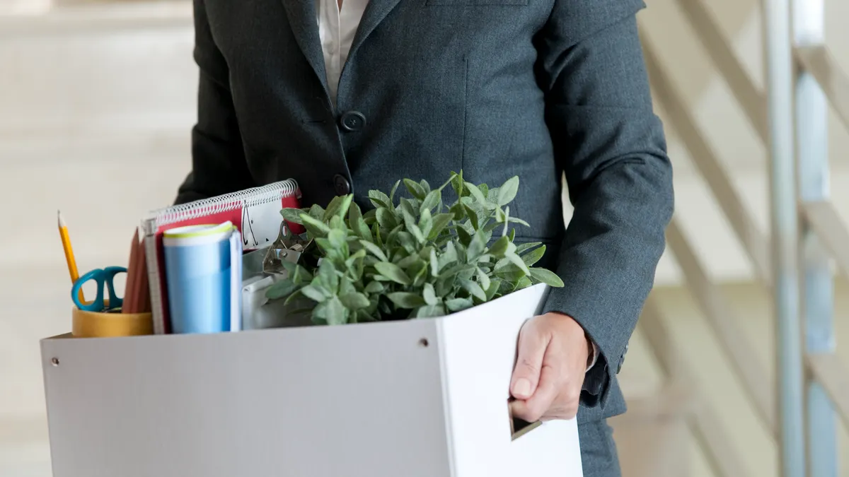 Mid Section View of a Businesswoman Holding a Cardboard Box Containing a Large Group of Objects