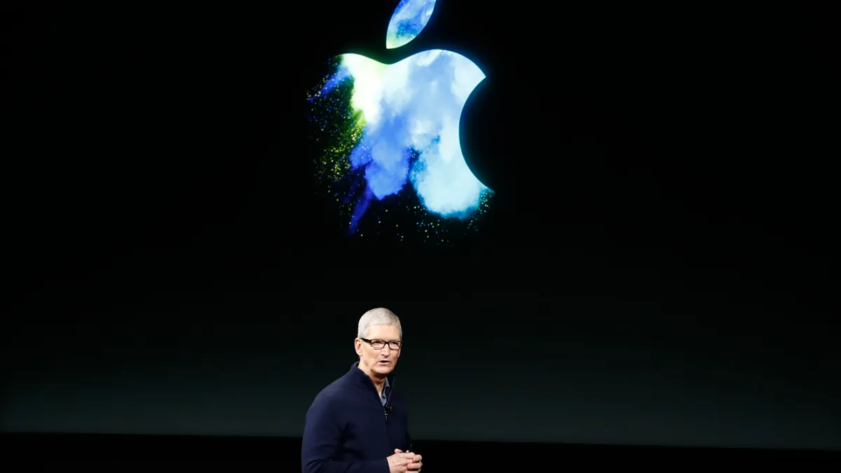 A man in a black shirt against a black background with the apple logo in blue