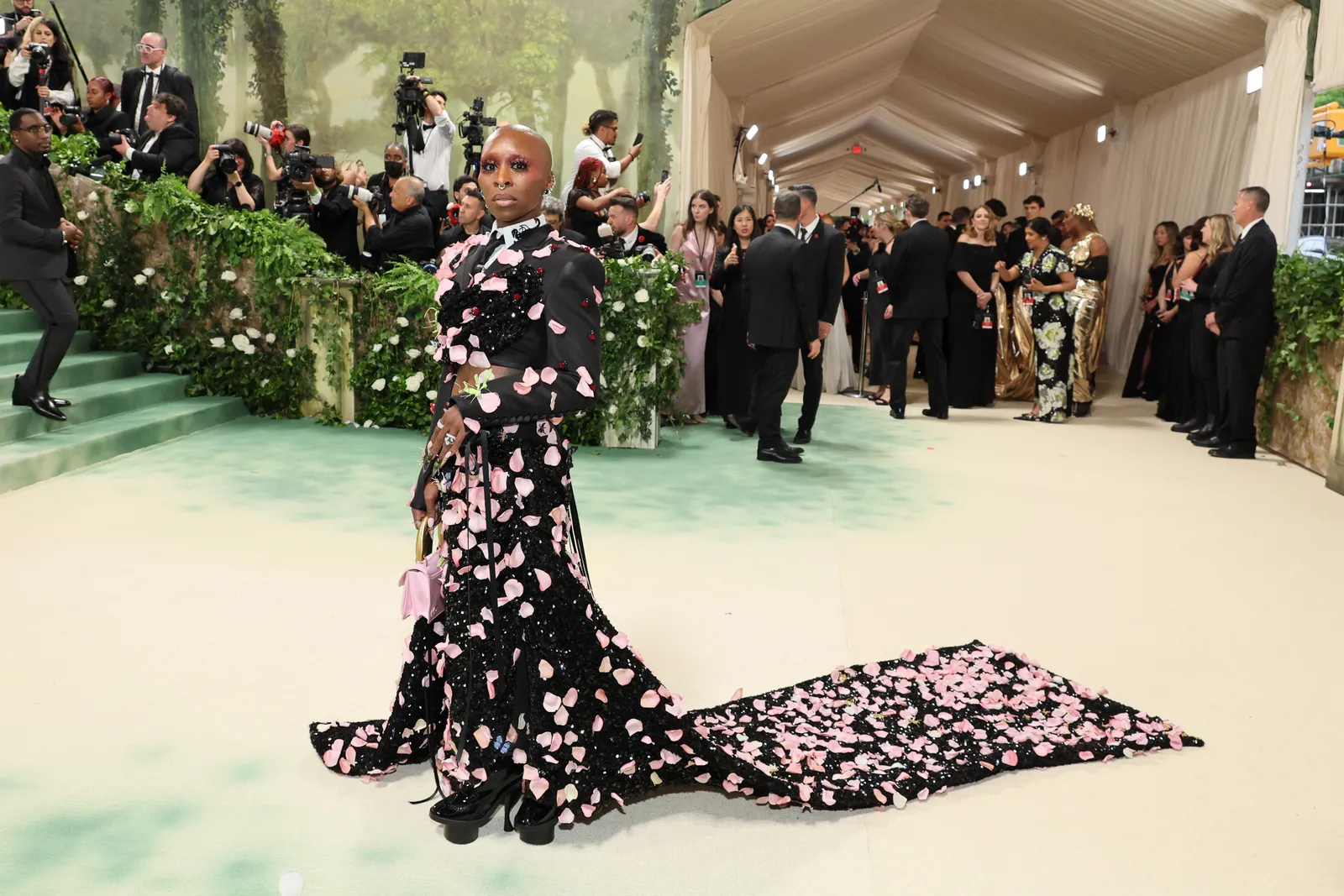 A person in a suit covered in flowers stands in front of a line of photographers.