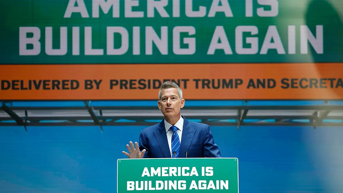 Transportation Secretary Sean Duffy stands at a podium, with sign reading "America is building again."