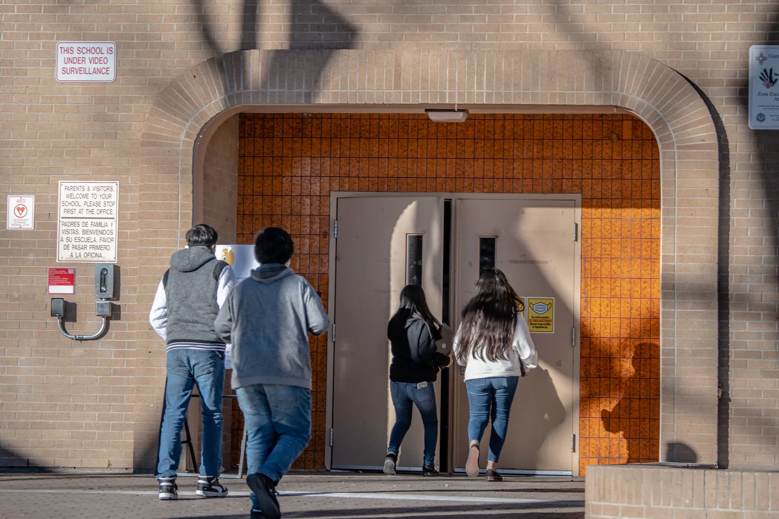 Four people are shown walking into a school building with their backs toward the camera. Above the door entrance, letters read Washington Middle School.