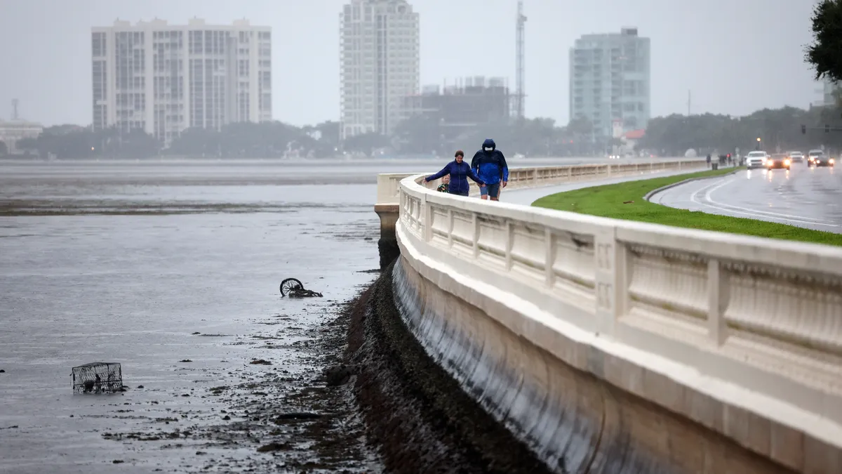 High-rises in the distance. People walking along boulevard in the rain in the foreground.