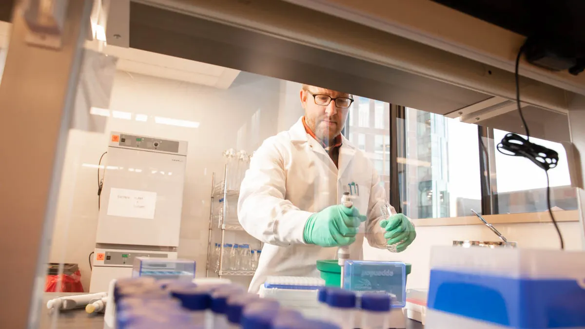 A man in a laboratory holds research equipment.