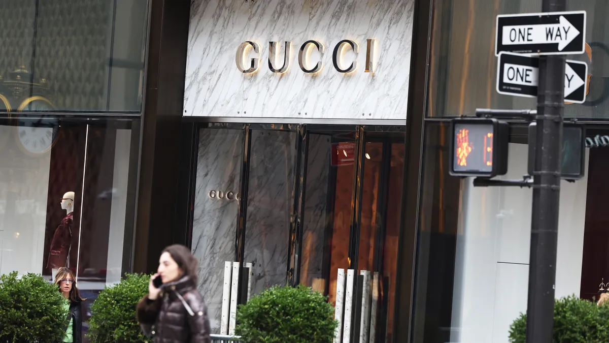 People walk in front of a Gucci storefront.