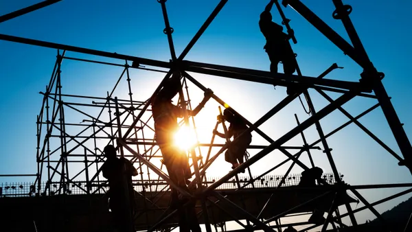 Construction workers climb scaffolding on a jobsite.