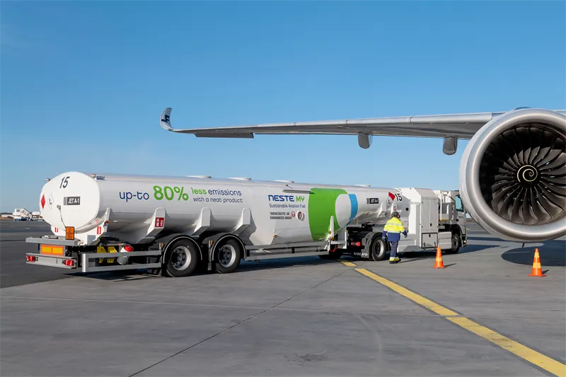 A truck full of NESTE SAF refuels an airplane sitting on a tarmac.