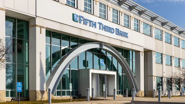 A modern glass arched facade with a Fifth Third Bank sign is displayed above the revolving door entrance. 