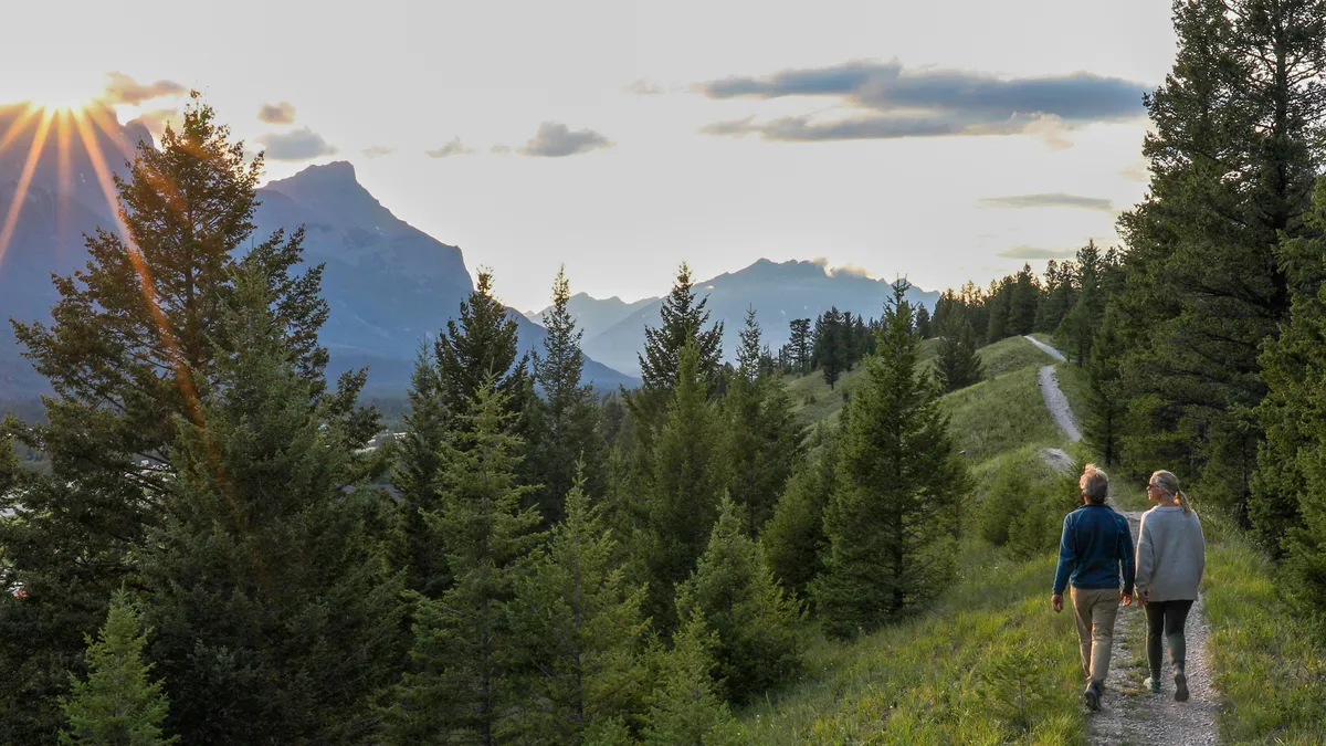 Two hikers walk along a trail.