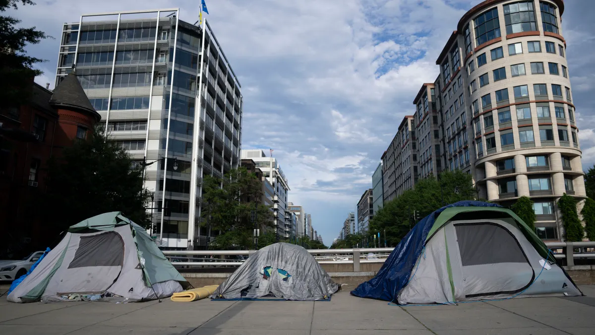 Three worn tents on a city sidewalk