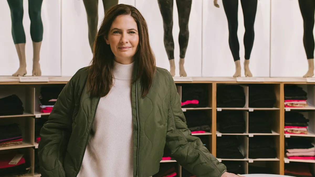 A headshot of Elizabeth Binder in front of a wall of leggings.