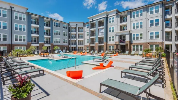 Light colored mid-rise apartments surrounding a pool.