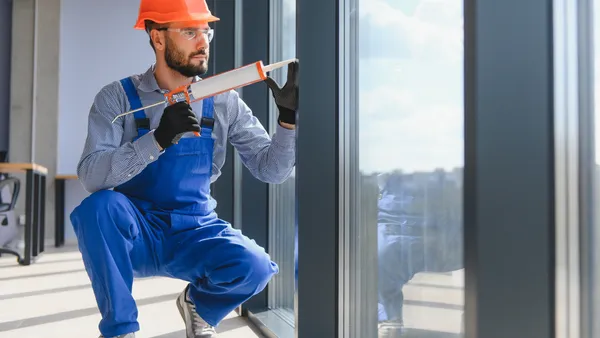 A worker installs a plastic window indoors