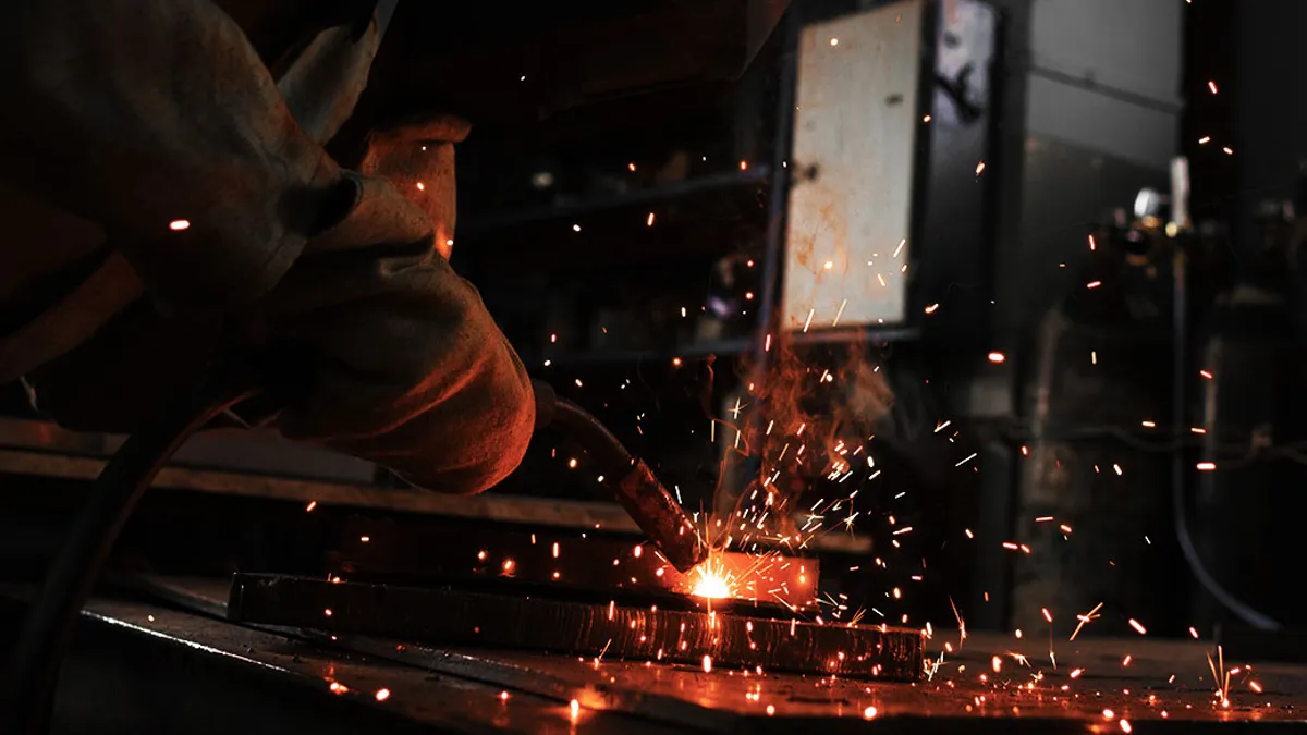 Manufacture worker welding metal with sparks at factory