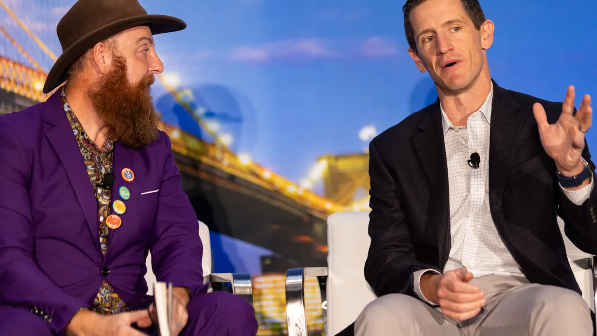 Two people sit on a stage for a fireside chat at a conference.