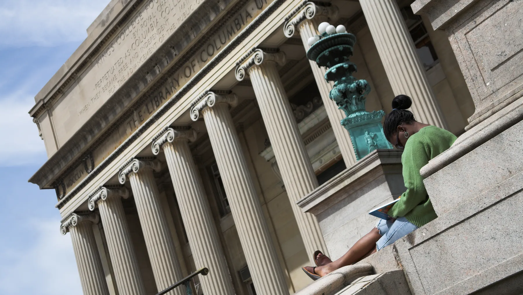 A person sits outside a Columbia University library building.