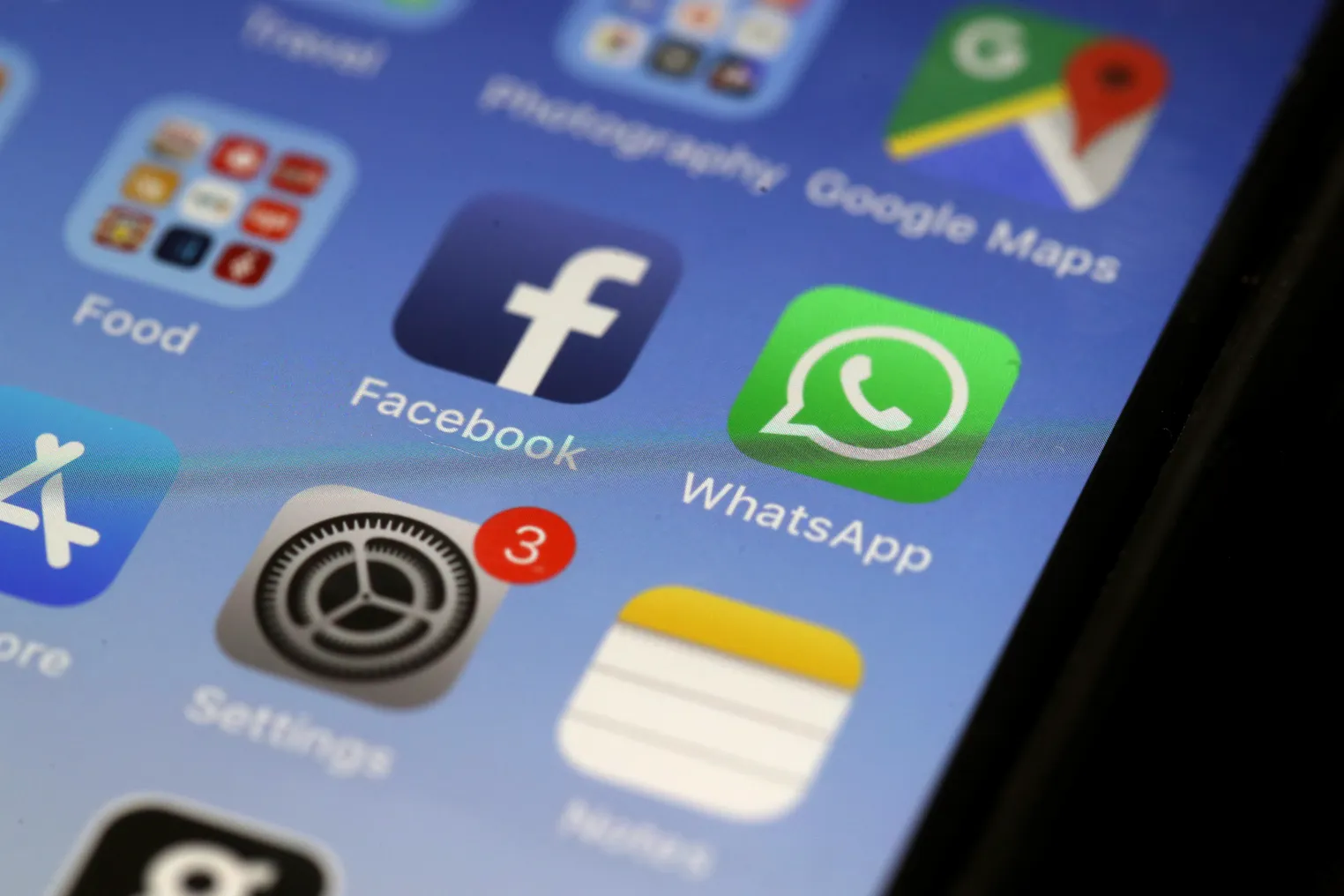 Icons of Facebook, WhatsApp and Settings appear on a lit phone screen.