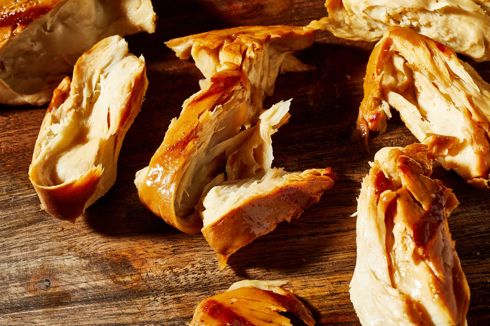 Pieces of roasted and cooked cultivated chicken on a wooden cutting board